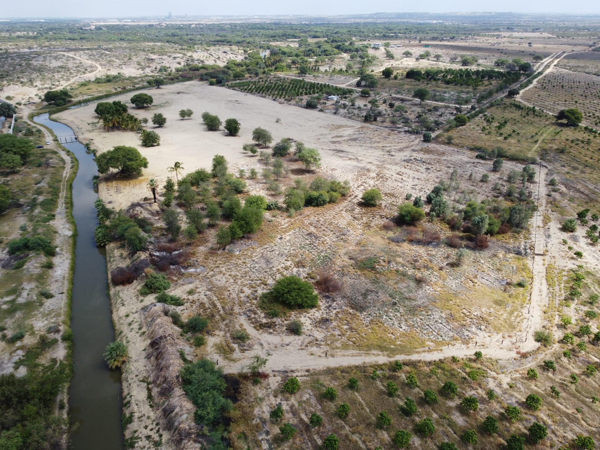 Vista aérea real del canal de agua bordeando Finca Los Cocos, Piura